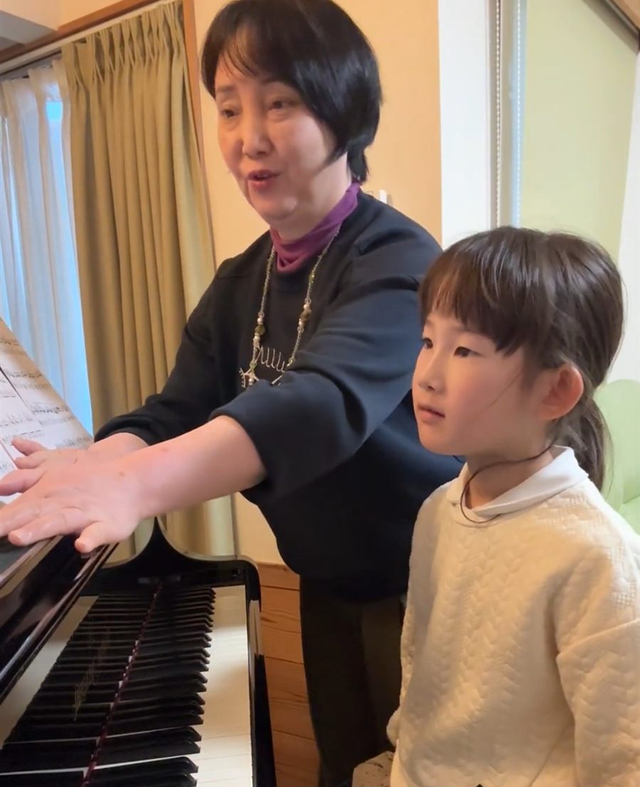 教室のグランドピアノで、先生がお手本を弾いて見せているレッスン風景